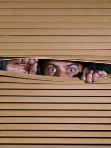 Man spying on something through venetian blinds